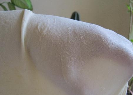 1. Этап. Выпечка из теста фило: 6. Руки обильно присыпьте мукой, возьмите раскатанный пласт теста фило и тыльной стороной ладоней на весу начинайте растягивать его, постепенно от середины к краям одновременно крутя вокруг своей оси.