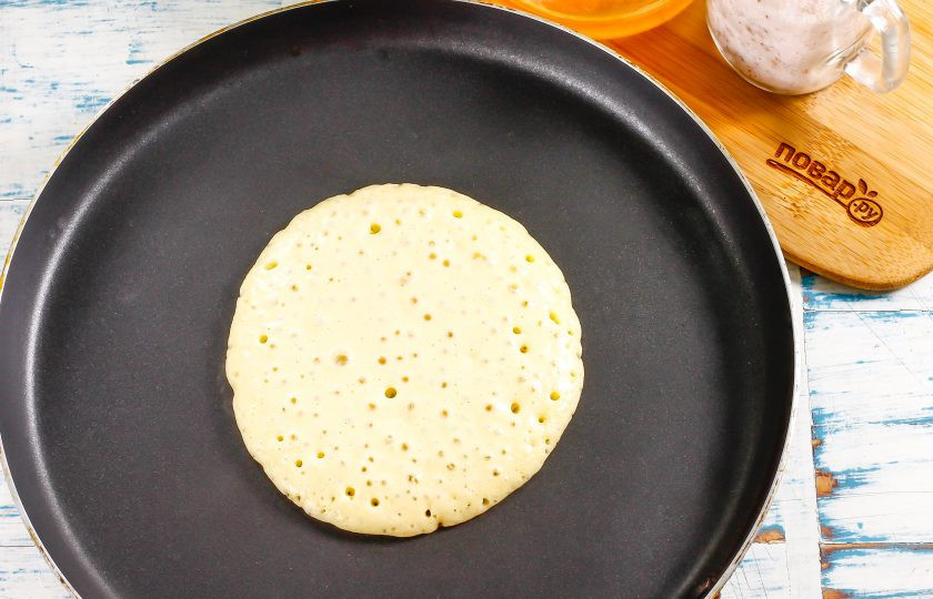 1. Этап. Толстые блины без дрожжей: Блинную сковороду прогрейте на умеренном нагреве. Ее смазывать ничем не нужно. Влейте на середину емкости половину половника теста и обжарьте до того момента, когда пузыри на поверхности теста начнут лопаться.