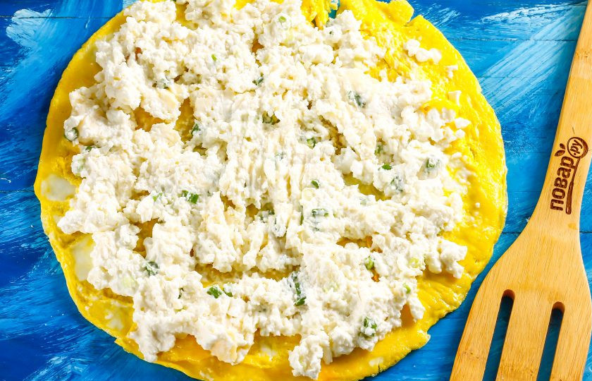 1. Этап. Рулет на год Крысы: Выложите омлет на доску или тарелку, на омлет выложите творожную массу и аккуратно распределите по всей поверхности.