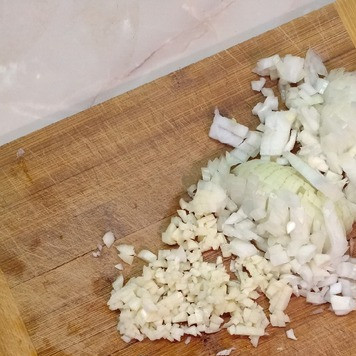 1. Этап. Кабачки, фаршированные рисом и тушенкой: Лук и чеснок очистить и мелко нарезать.