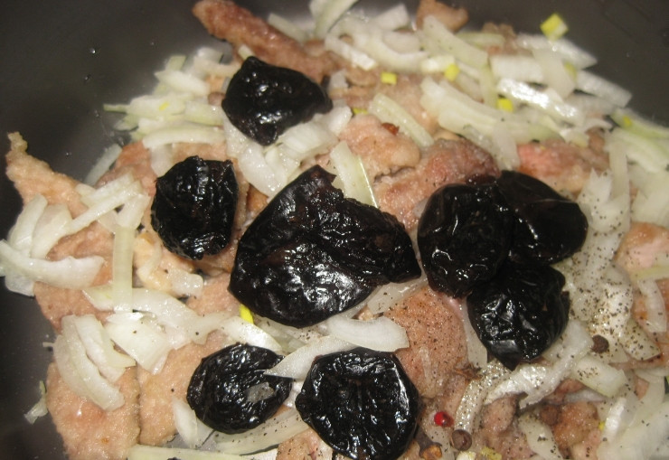 1. Этап. Гуляш из телятины в мультиварке: Добавляем к мясу нарезанный лук и промытый чернослив, а также специи.