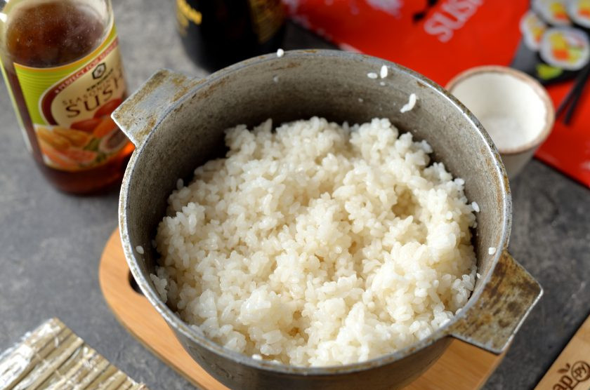 1. Этап. Роллы с тунцом и кунжутным соусом: Рис тщательно промойте до чистой воды, раз 7-8 точно. Залейте питьевой водой, чтобы она была выше крупы на 1 сантиметр, поставьте на сильный огонь. Как только вода закипит, сделайте огонь под казаном самым тихим, плотно накройте крышкой, варите 15 минут. Затем выключите плиту, снимите казан, выложите несколько бумажных полотенец между крышкой и казаном, оставьте еще на 15 минут. Влейте заправку из уксуса с сахаром и солью, перемешайте, прикройте тем же бумажным полотенцем, но уже без крышки и оставьте до остывания.