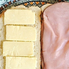 1. Этап. Сэндвич Монте-Кристо: 1. Сыр нарежьте ломтиками. Выложите на кусочек батона два ломтика ветчины, один ломтик сыра и накройте вторым кусочком батона.