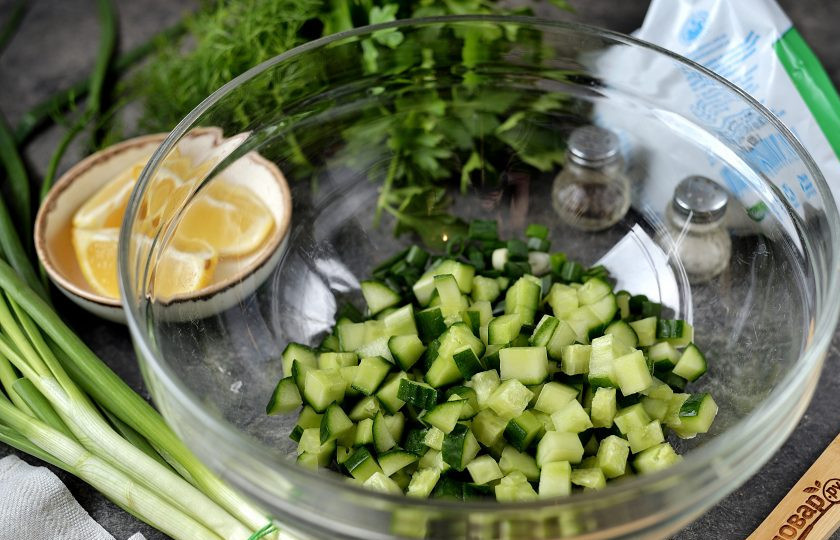 1. Этап. Летний суп на кефире: Подготовьте глубокую большую миску, выложите в нее мелко нарезанный зеленый лук и чеснок, огурец нарежьте мелким кубиком.