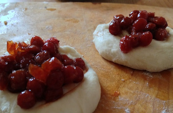 1. Этап. Пирожки с клюквой: 4. Самое время лепить пирожки. Кусочек теста нужно размять и превратить в лепешку. В середину выложить клюкву в сахаре и залепить края.