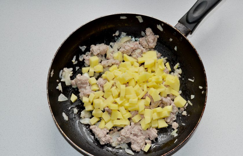1. Этап. Штрудель с мясом, картошкой и капустой: Очистите и нарежьте мелким кубиком картофель. Добавьте на сковороду.