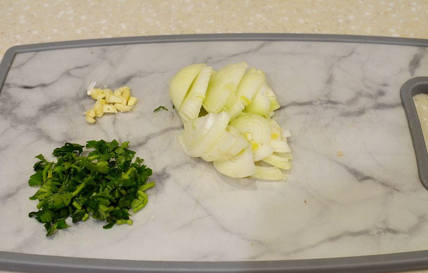 1. Этап. Куриные желудки по-грузински: Лук нарежьте полукольцами, чеснок и зелень измельчите.