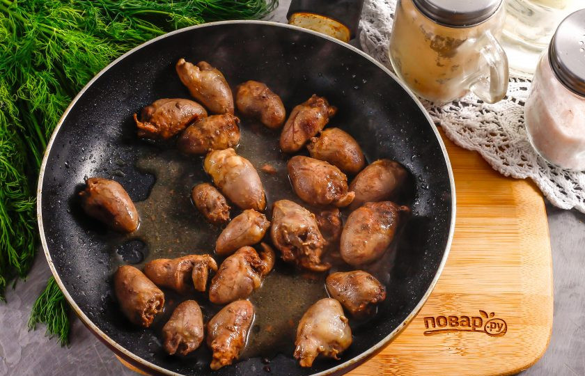 1. Этап. Теплый салат с куриными сердечками: Далее обжарьте на оставшемся растительном масле куриные сердечки. На это у вас уйдет не менее 12-15 минут, так как субпродукты сначала выделят жидкость, которую нужно будет выпарить, и только после этого начнут подрумяниваться. В этот момент обязательно накройте сковороду крышкой, так как сердечки будут подпрыгивать и могут разлететься по всей плите.