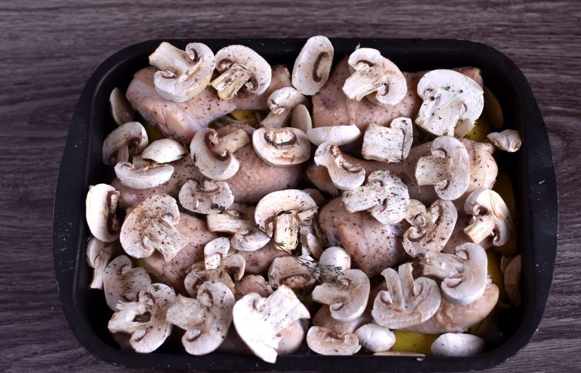 1. Этап. Куриные ножки с картошкой и грибами: С шампиньонов снимите верхнюю кожицу и нарежьте толстыми ломтиками. Достаньте форму из духовки и выложите грибы поверх курицы. Немного посолите, поперчите и добавьте тимьян, а пару лавровых листиков положите вглубь формы на картошку. Запекайте до румяной корочки на грибах.