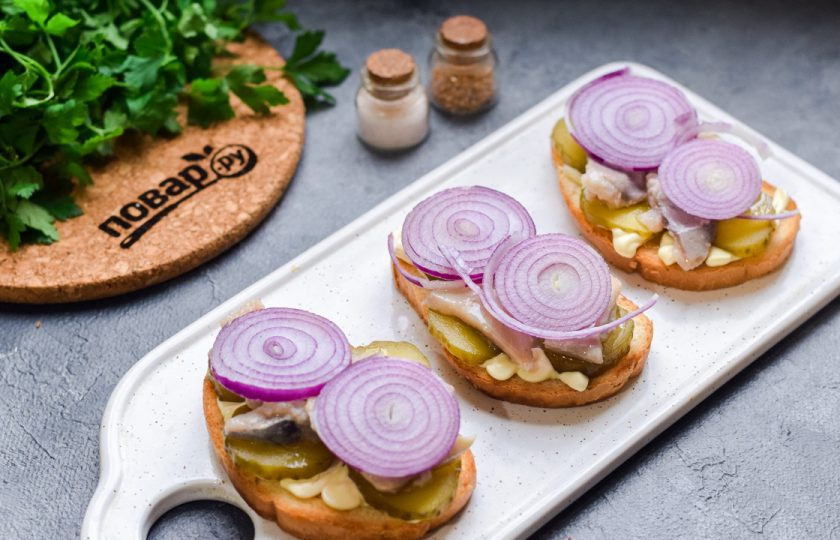 1. Этап. Голландские бутерброды с селедкой: Лук нарежьте кольцами и выложите поверх рыбы.