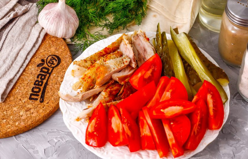 1. Этап. Азербайджанская шаурма: Срежьте мясо с обжаренных куриных голеней, нарежьте его полосками. Промойте помидоры и вырежьте зеленые сердцевинки. Нарежьте томаты ломтиками, а соленый огурец — брусочками. По желанию можно использовать свежий огурец.